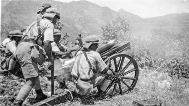 Soldiers beside an old cannon in a mountainous area