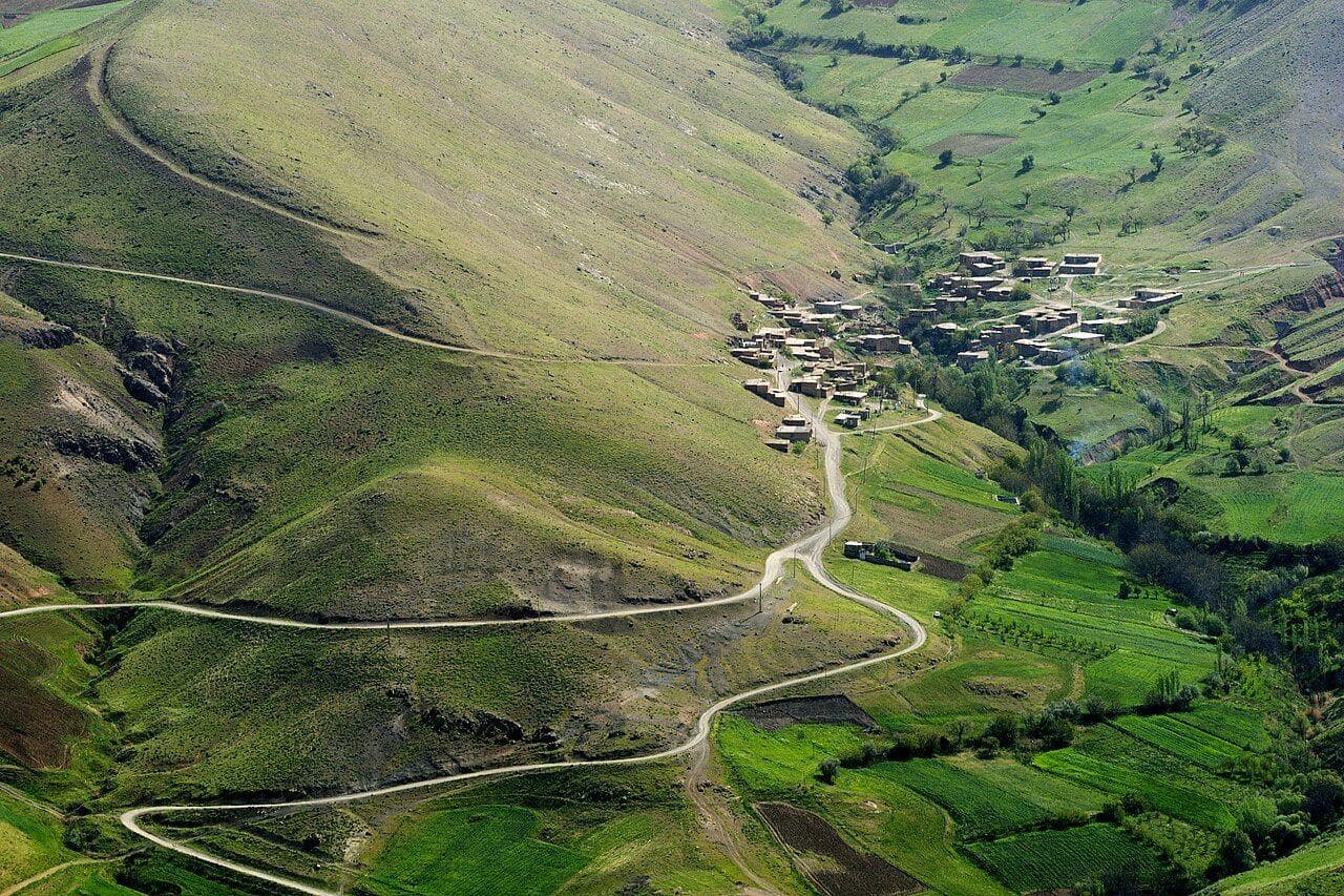 A winding road towards a village among the fields